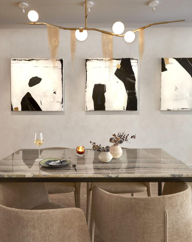 A single glass of Neverstill white wine on a marble table beneath abstract canvases in the tasting room. Photograph by Theo Coulombe.